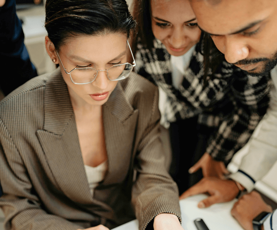 Woman with glasses examining documents with other people surrounding her.